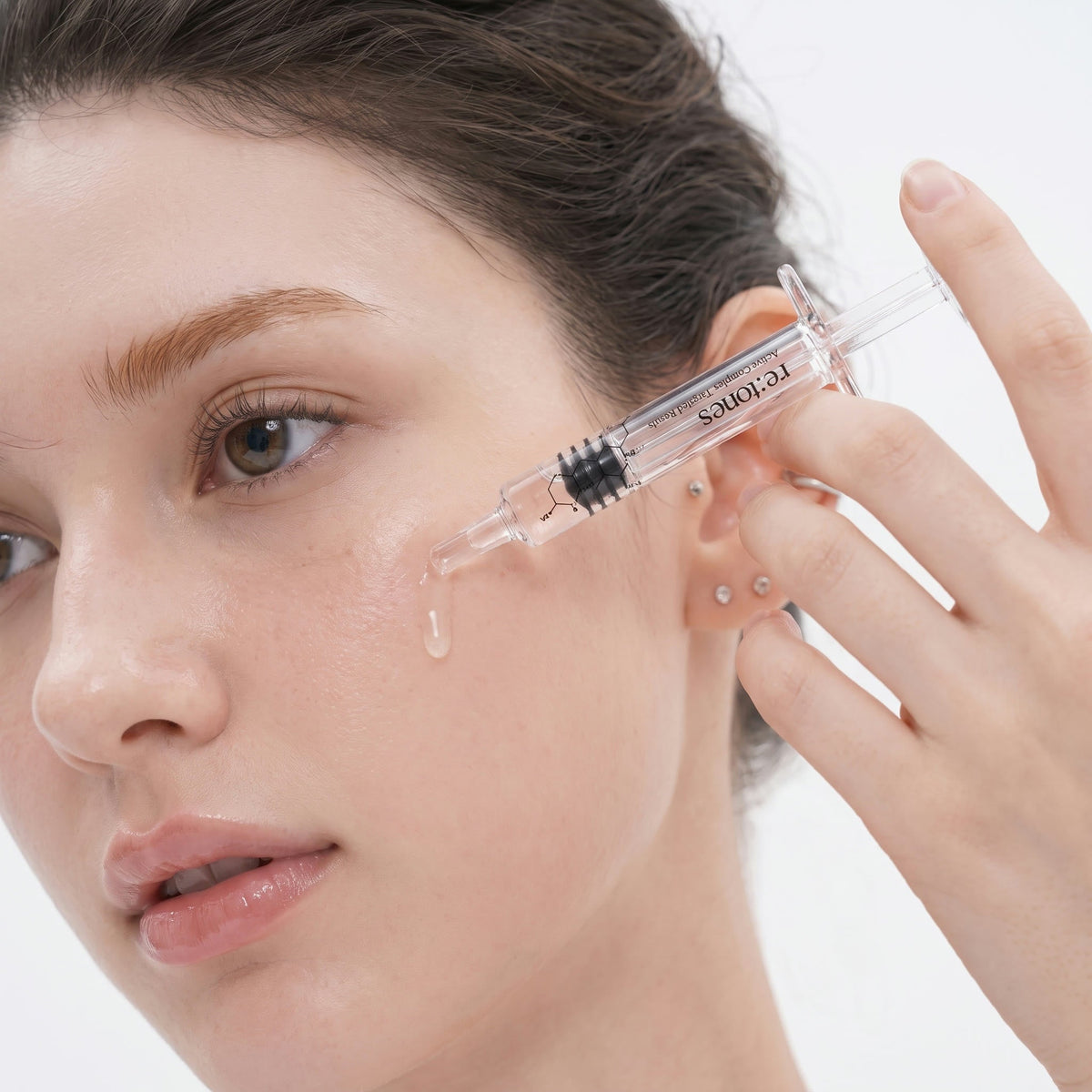 The ampoule being applied to the cheek with the included 1 mL syringe.