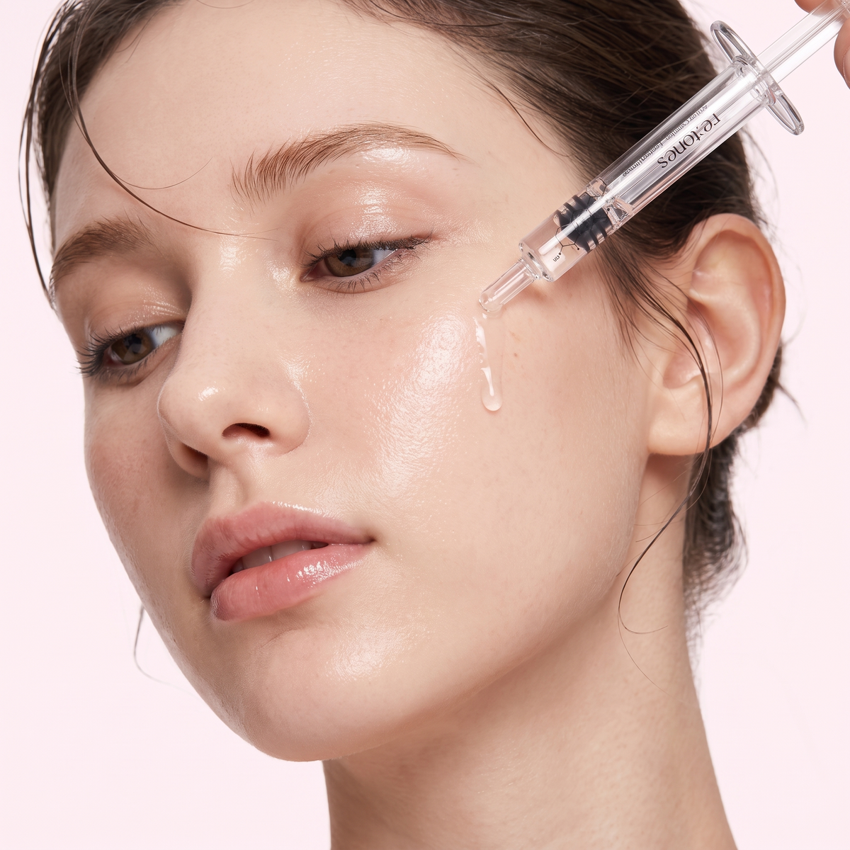 A woman applying the re:tones wrinkle peptide ampoule to her cheek with the supplied glass applicator