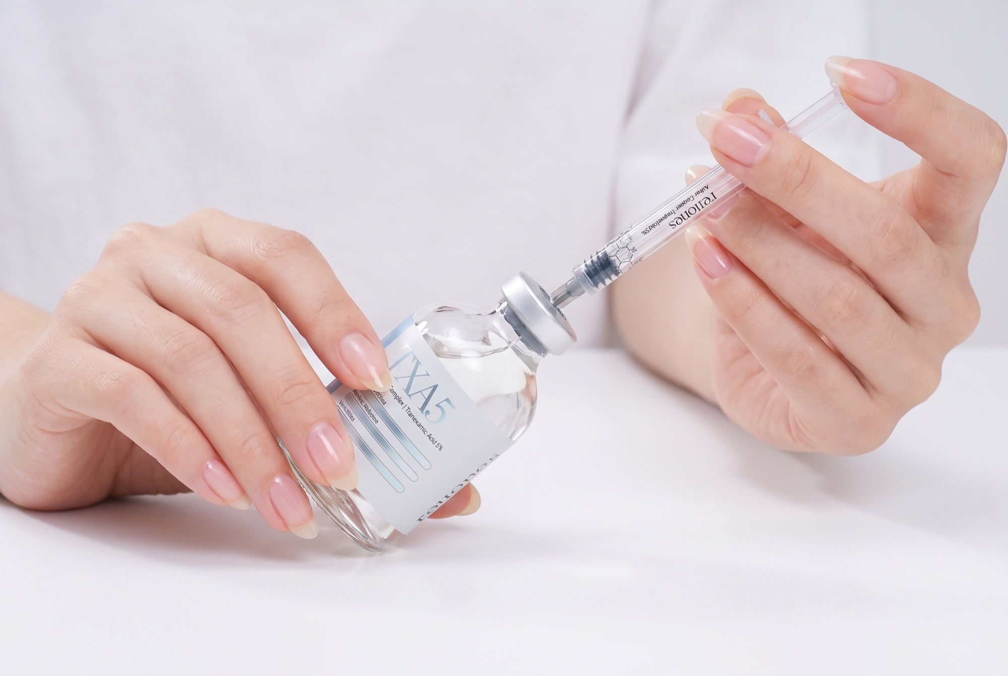 The applicator tip pressed through the rubber seal at the center of the vial's aluminum crimp cap