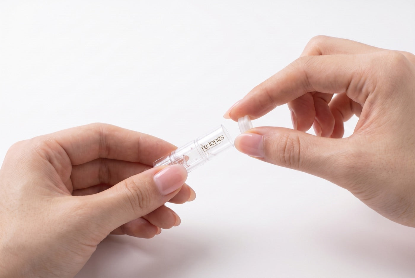 Two hands lifting the cap off the top of a clear cartridge